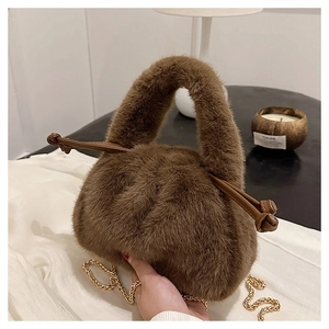 Detail einer weichen braunen Kunstpelz-Handtasche mit stilvollen Quasten und goldener Kette