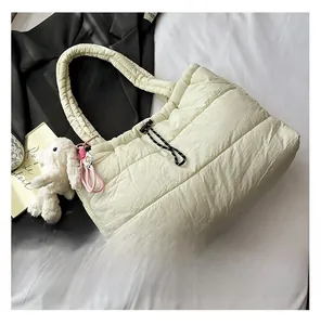 Detail of off-white quilted tote bag with drawstring closure and plush bunny charm