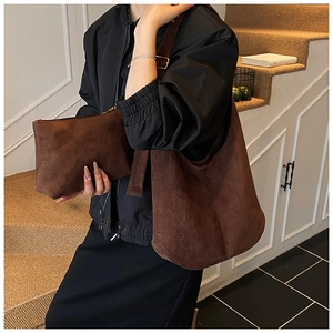 Détail du sac bandoulière en daim marron avec pochette assortie sur un escalier vintage