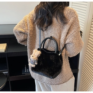 Detail einer schwarzen Plüsch-Handtasche mit runden Griffen und Hasenanhänger
