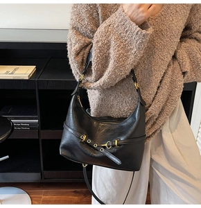 Dettaglio della borsa hobo in pelle cerata nera con fibbie metalliche e borchie decorative