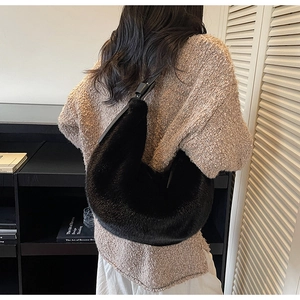 Detail of black faux fur crescent hobo bag with leather strap on a model's shoulder