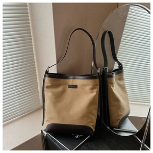 Detail view of canvas bucket bag with brown leather trim reflecting in a round mirror