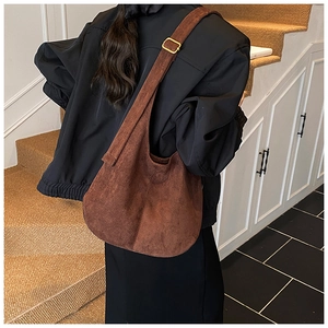 Sac seau en daim marron vu de dos sur l'épaule avec boucle métallique dorée
