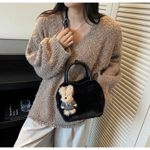 Detailansicht der schwarzen Plüsch-Handtasche mit Teddybär-Anhänger getragen am Modell