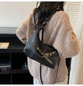 Dettaglio borsa hobo nera a mezzaluna con fibbia dorata e tracolla minimalista