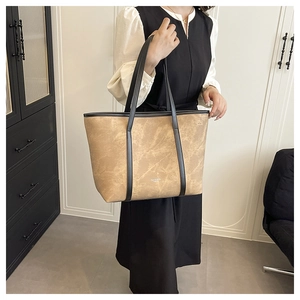 Detailed view of spacious brown tote bag with black leather straps and brand lettering