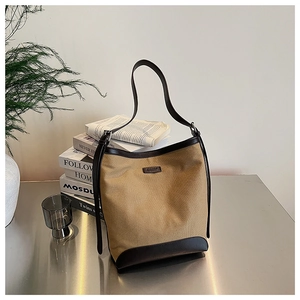 Detail of minimalist khaki canvas bucket bag with dark brown leather trim and metal surface