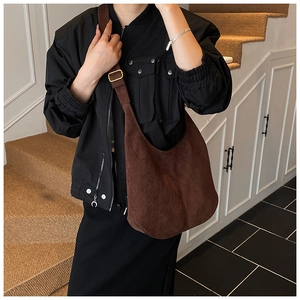 Détail du sac hobo en daim marron foncé avec large bandoulière et boucle dorée