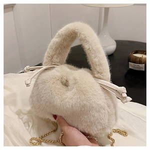 Detailaufnahme der cremefarbenen Plüschtasche mit Goldkette und Kordelzug