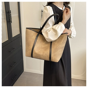 Close-up of vintage brown leather tote bag with black straps on model shoulder