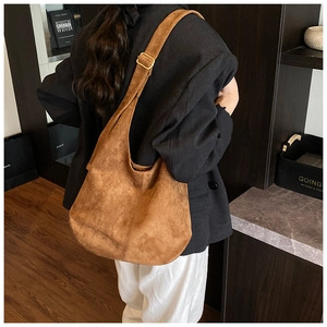 Sac hobo en daim marron porté épaule montrant le drapé élégant et la bandoulière