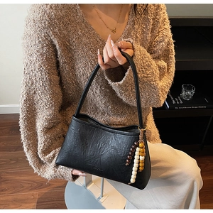 Detail of black pleated leather shoulder bag with vintage wooden beads and logo engraving