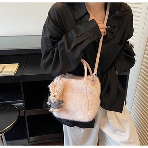 Details der rosa Kunstfell-Handtasche mit Ledergriffen und süßem Bärenanhänger