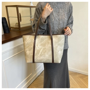 Detail of beige marble texture tote bag with brown leather straps held by a model