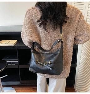 Dettaglio di una borsa hobo vintage nera con fibbia dorata e ampia tracolla in pelle