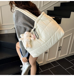 Detail of quilted puffer tote bag in cream white with a cute plush bunny charm