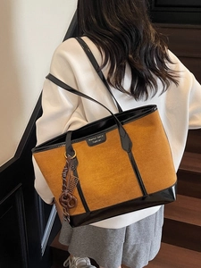Borsa tote in camoscio marrone con finiture in pelle nera e ciondoli indossata dal modello