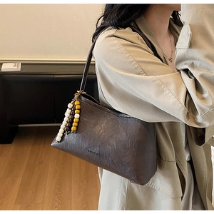 Detail of vintage brown leather underarm bag with wooden bead tassel and logo branding
