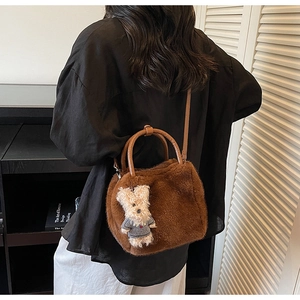Detail der braunen Plüschtasche aus Kunstfell mit Ledergriffen und süßem Bärenanhänger