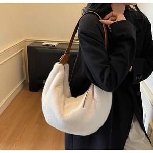 Close-up of white plush half-moon bag featuring an adjustable brown leather strap