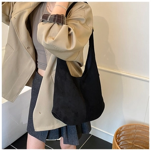 Détail macro du grand sac hobo en daim noir avec large bandoulière porté par un mannequin