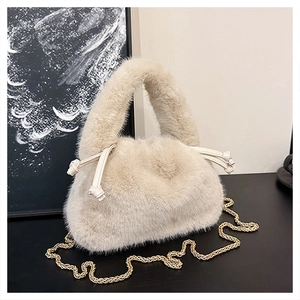 Detail der flauschigen cremefarbenen Kunstfelltasche mit Goldkette und Knotendesign