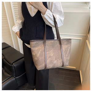 Close-up of brown marble pattern tote bag with leather strap and logo detail