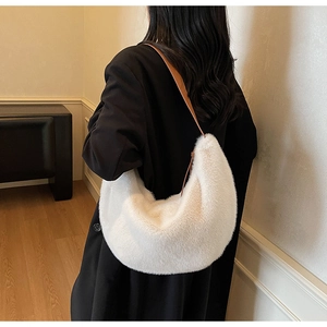 Detail of white fluffy plush crescent bag with brown leather shoulder strap on a model