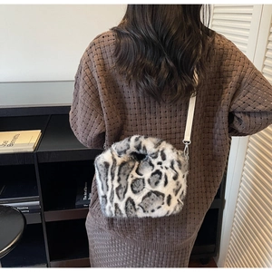Detail der Plüsch-Umhängetasche mit Leopardenmuster und weißem Riemen am Strickpullover