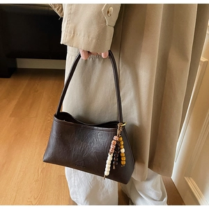 Detail of dark brown vintage shoulder bag with textured faux leather and beaded tassel