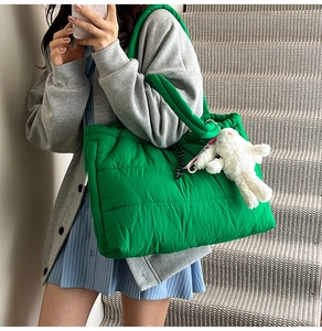 Close-up of bright green quilted tote bag with a soft white plush bunny charm accessory