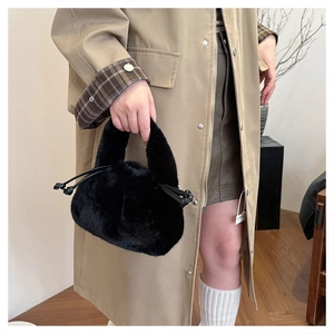Detailansicht der schwarzen Kunstpelz-Handtasche mit weicher Textur und seitlichem Knoten