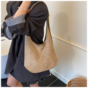 Texture détaillée d'un grand sac hobo en daim kaki porté à l'épaule par un mannequin