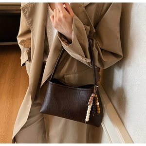 Close-up of vintage dark brown leather shoulder bag with ethnic beaded charm detail