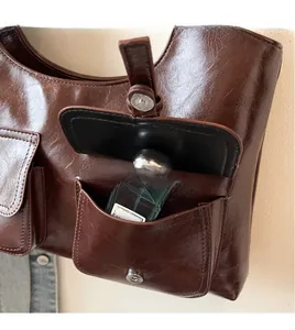 Detail of vintage brown tote featuring a functional front pocket with magnetic metal clasp