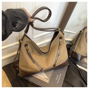 Detail of canvas bucket bag with brown faux leather trim and diagonal zipper accents