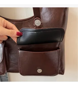 Detail of glossy dark brown faux leather tote with round silver metal snap fastener