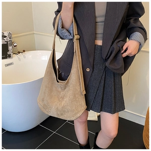 Gros plan du sac hobo en daim camel avec large bandoulière et boucle dorée élégante