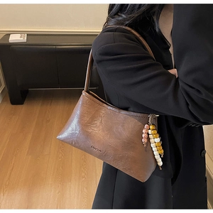 Close-up of vintage brown PU leather shoulder bag with colorful wooden bead tassel