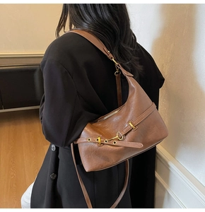 Dettaglio borsa hobo in pelle oliata marrone scuro indossata da una modella in interni moderni