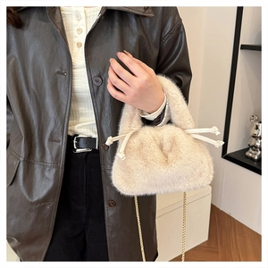 Detailansicht der cremefarbenen Plüschtasche mit Knotendetails und goldener Kette