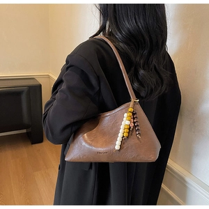 Close-up of brown vintage shoulder bag with ethnic wooden beads and leather texture
