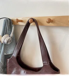 Detail view of brown leather tote bag with glossy wrinkled texture on wooden wall hook