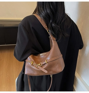 Borsa a tracolla vintage in pelle marrone indossata su un blazer nero casual