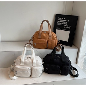 Three multi-pocket nylon travel bags in caramel, white, and black with wide straps