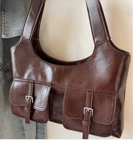 Detail of dark brown glossy leather tote featuring dual pockets with silver buckle accents