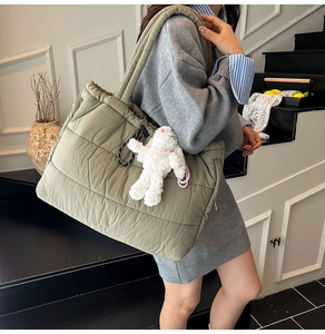Olive green quilted puffer tote bag shown on shoulder with a cute white bunny charm