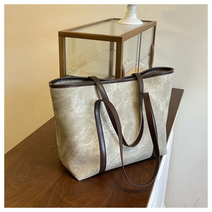 Detail view of large beige tote bag with marble texture and dark brown leather straps