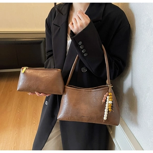 Detail of brown faux leather shoulder bag with beaded charm and matching zipper pouch
